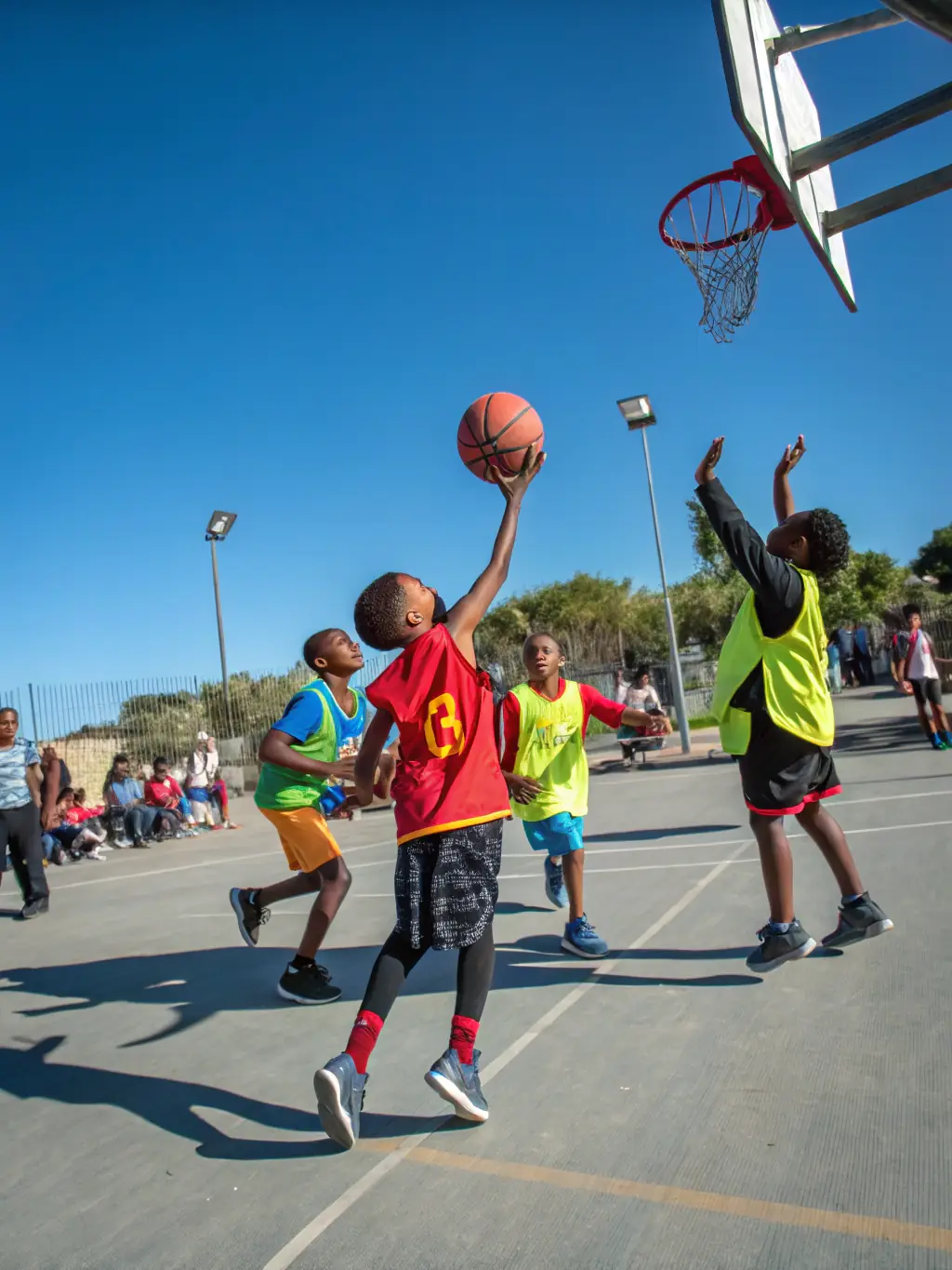 A group of children playing basketball outdoors, showcasing the fun and active environment of the sports program offered by ASSOCIATION VACANCES 93.